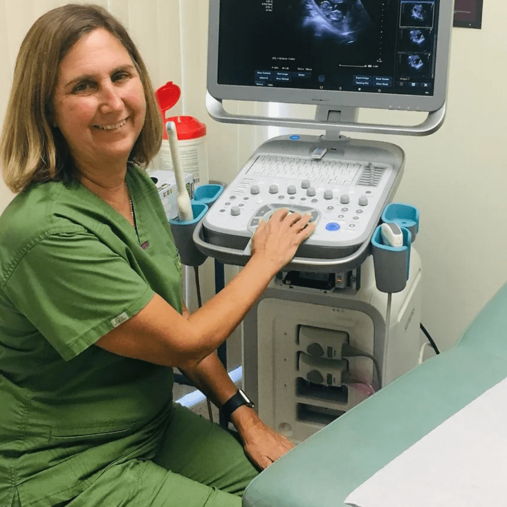woman smiling and operating an ultrasound machine